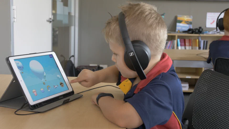 Young boy wearing headphones using Sound Scouts app on iPad.