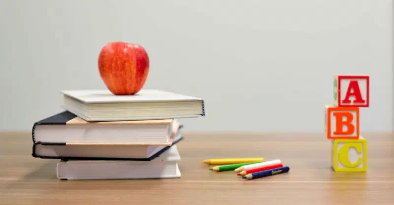 Books, apple and ABC cubes on desk to signify school related context