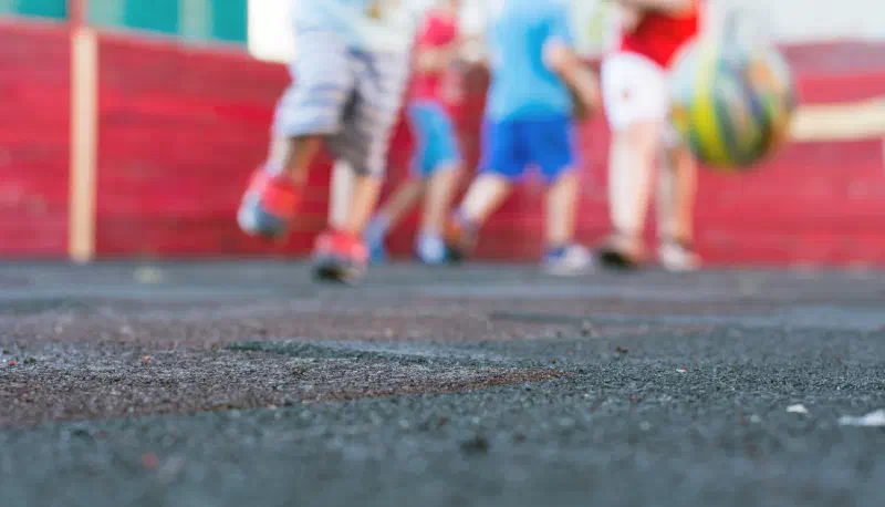 School Playground with four children and a bouncing ball in the background.