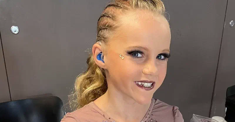 Portrait of Laila slightly side-on to see her blue in-ear hearing aid.
