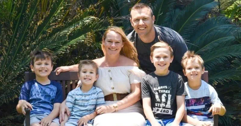 Lynell and her husband and three boys sat on a bench for a family photo