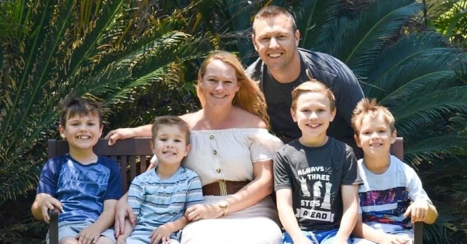Lynell and her husband and three boys sat on a bench for a family photo