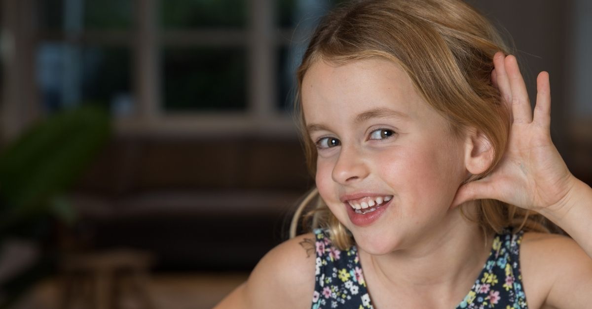 Child holding up hand to ear to listen