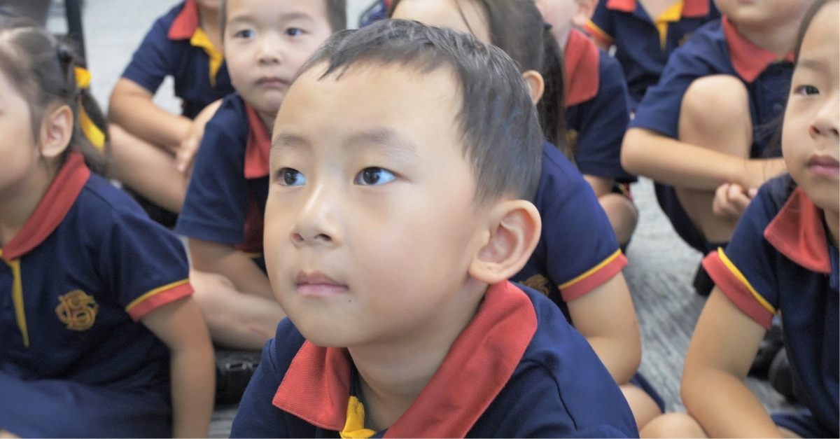 Children sitting on the ground of the classroom learning.