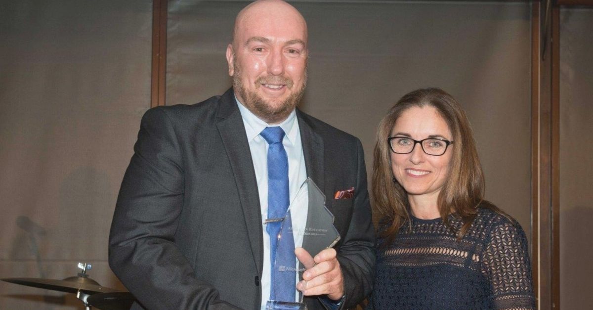 Carolyn and Paul McDermott standing side by side, Paul holding award